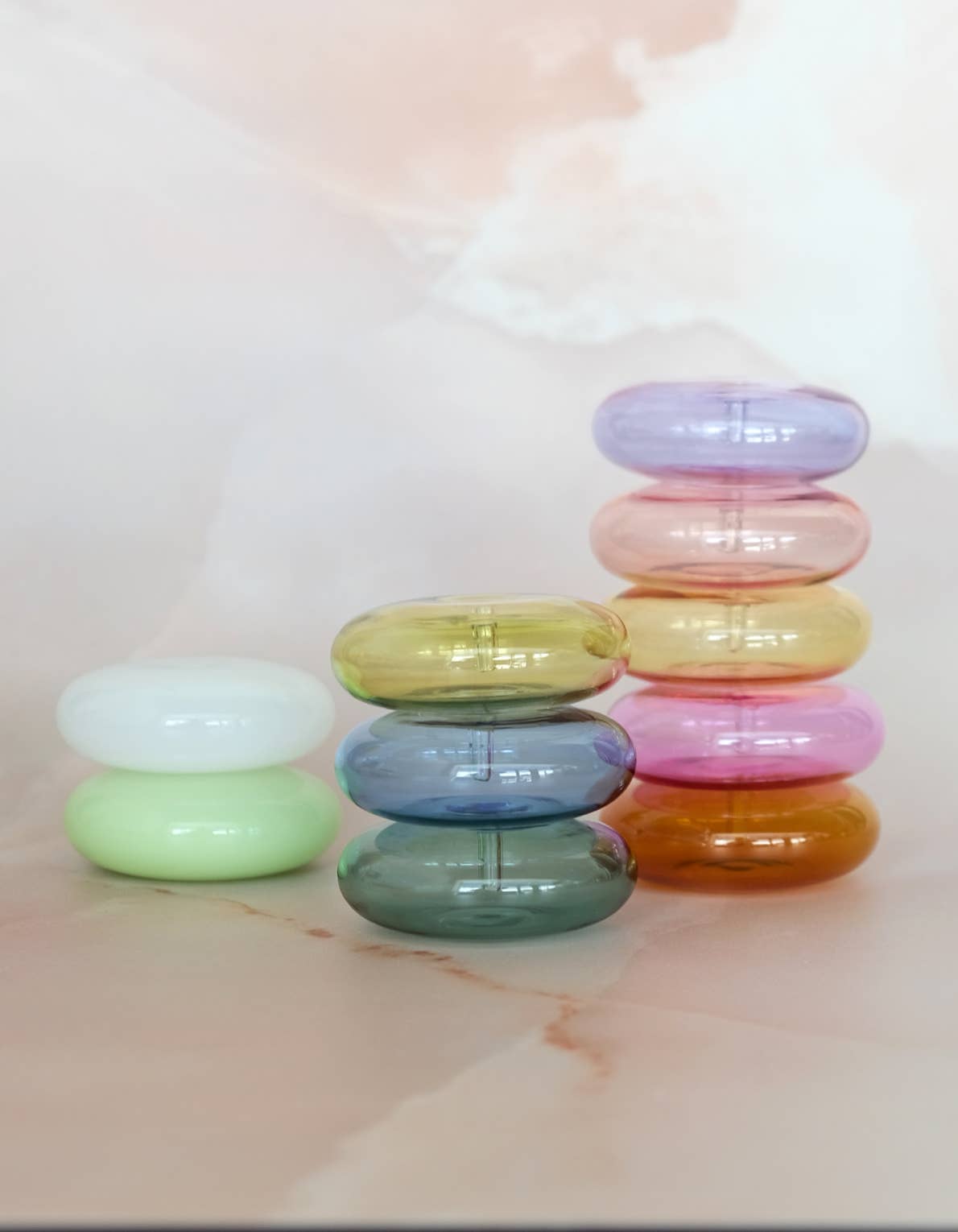 Stack of colorful transparent rings on a marble surface with a soft blurred background