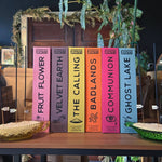 Row of incense boxes with colorful covers on a wooden table, surrounded by decorative elements.