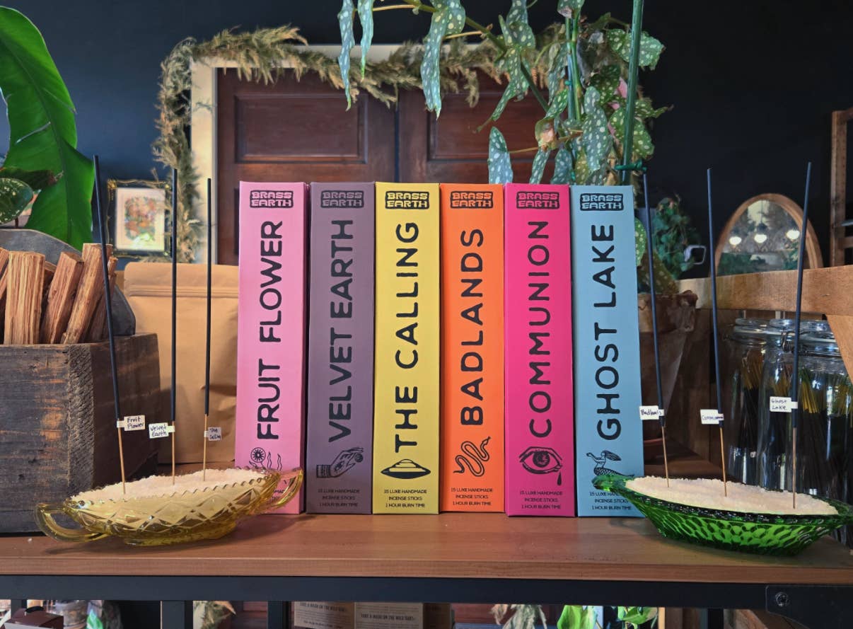 Row of incense boxes with colorful covers on a wooden table, surrounded by decorative elements.