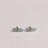 Pair of light blue earrings with gold accents on a beige background