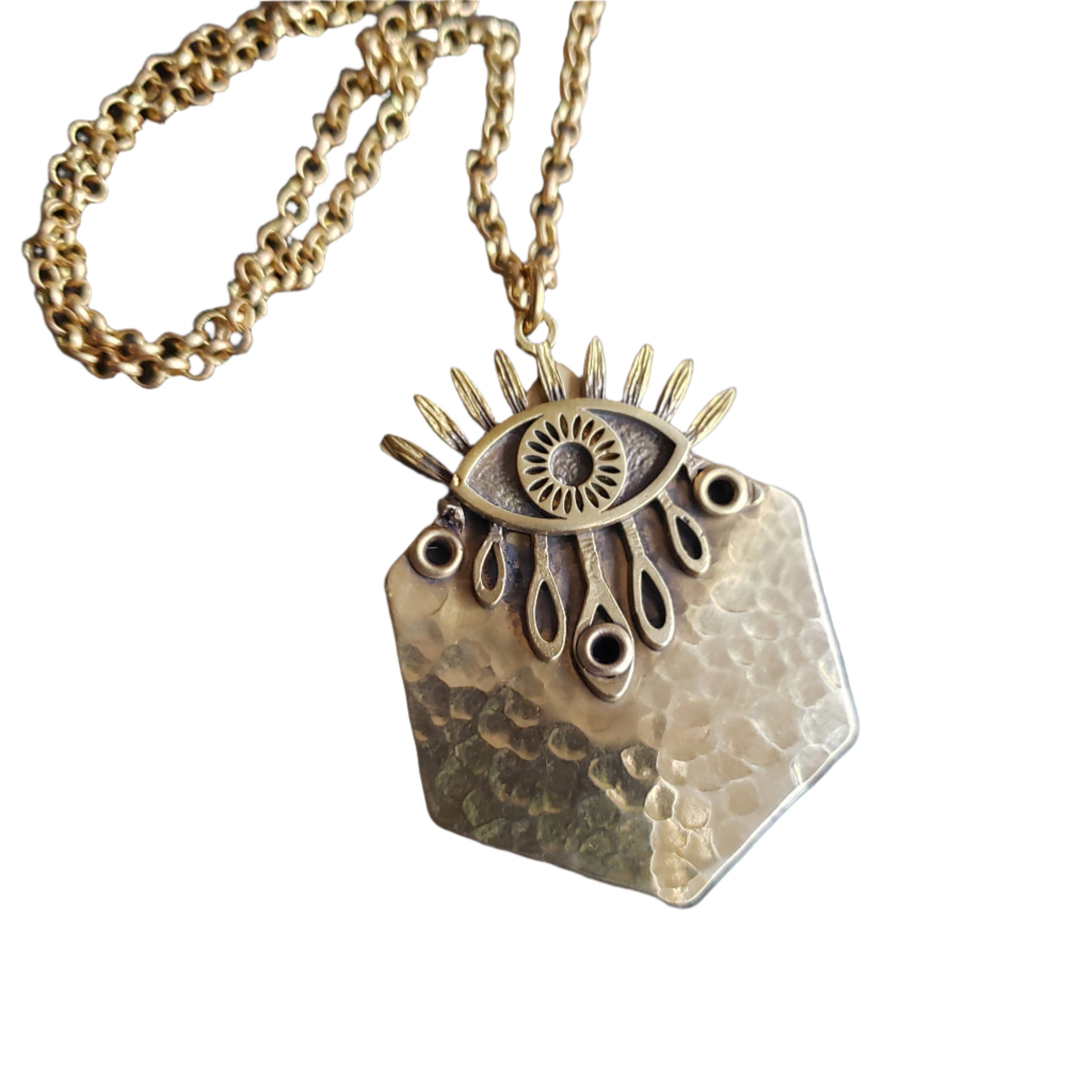 Gold pendant necklace with eye design on a dark textured background