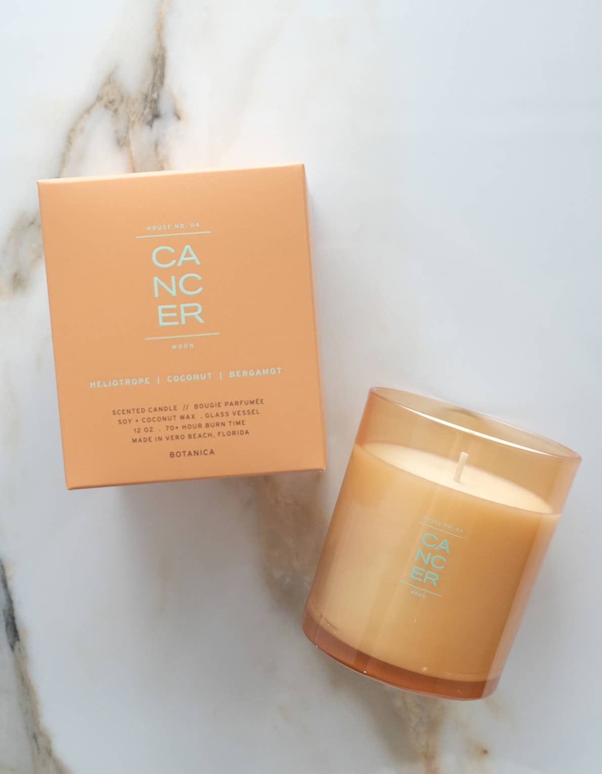 Candle labeled 'Cancer' with packaging on a marble surface