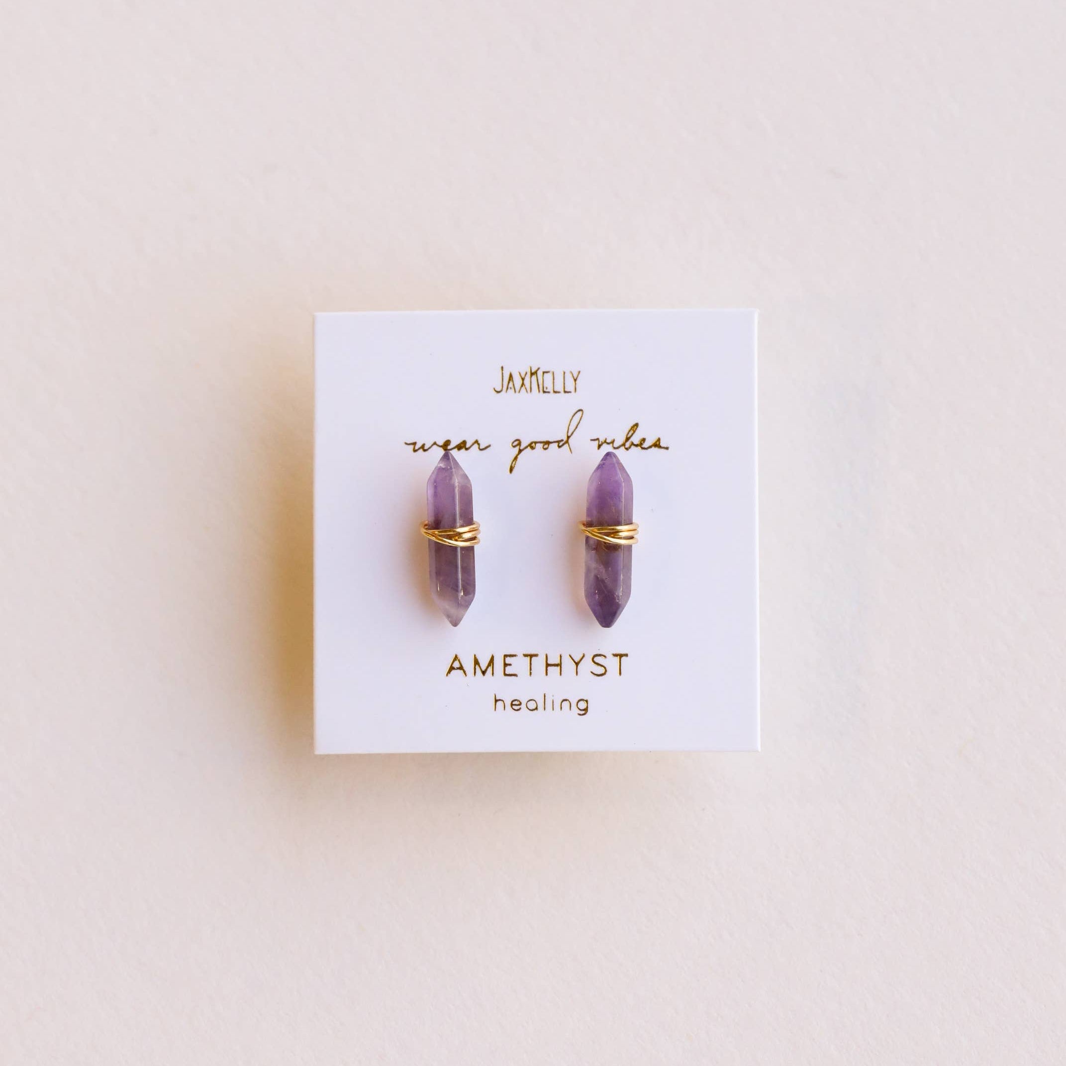 Amethyst earrings on a branded card with a light pink background