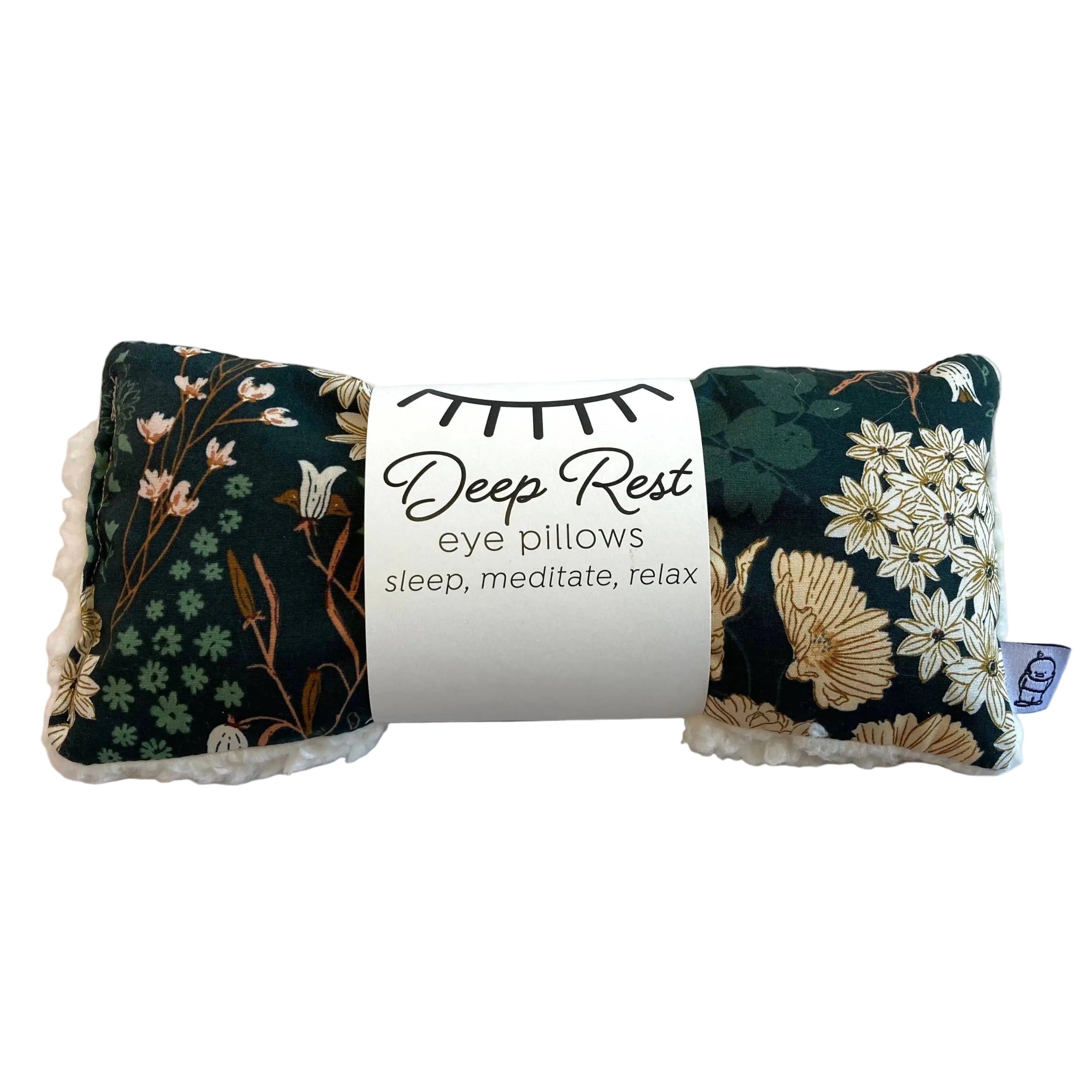 A dark green floral eye pillow with a label on a white background
