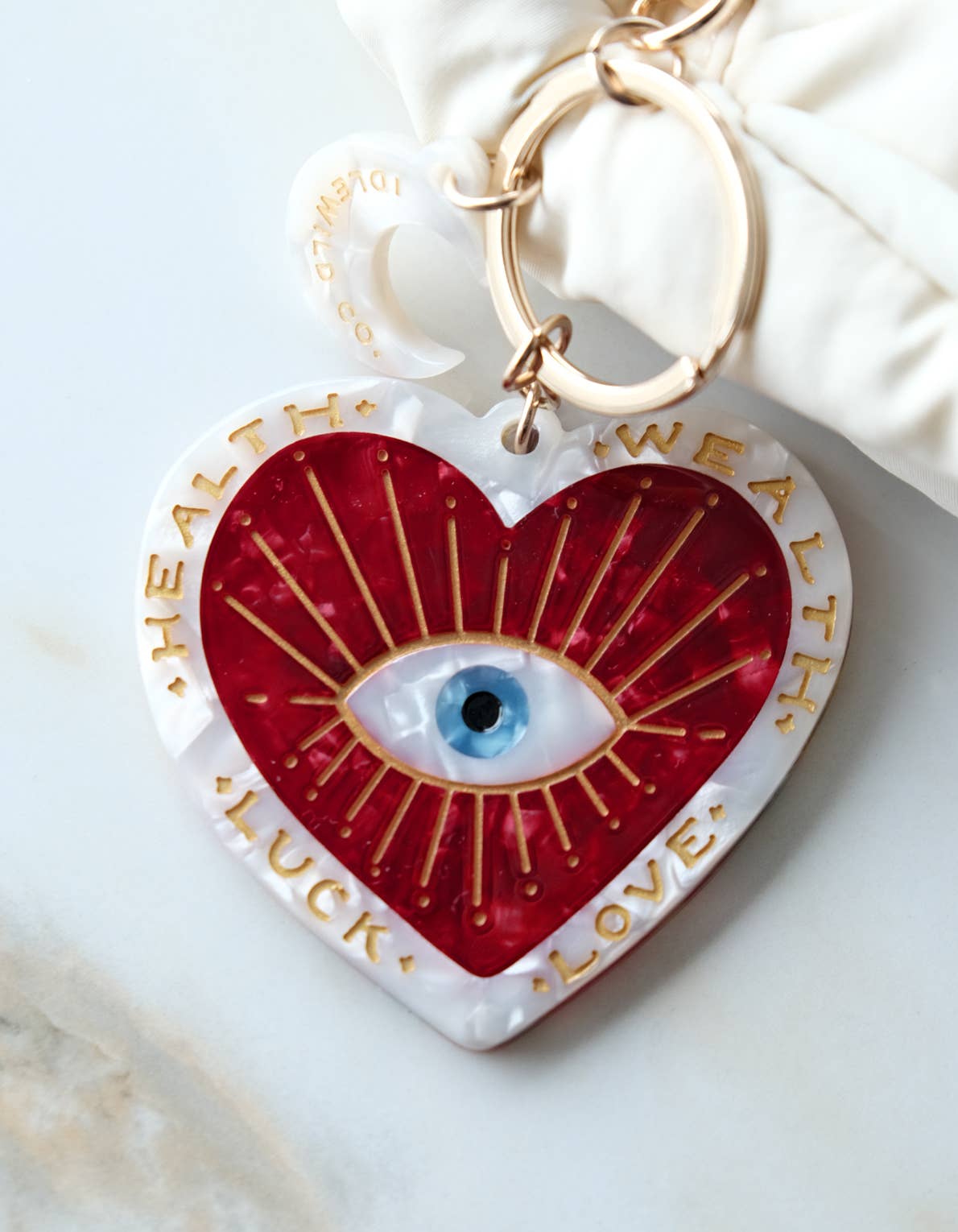 Heart-shaped keychain charm with eye design and text on a white surface
