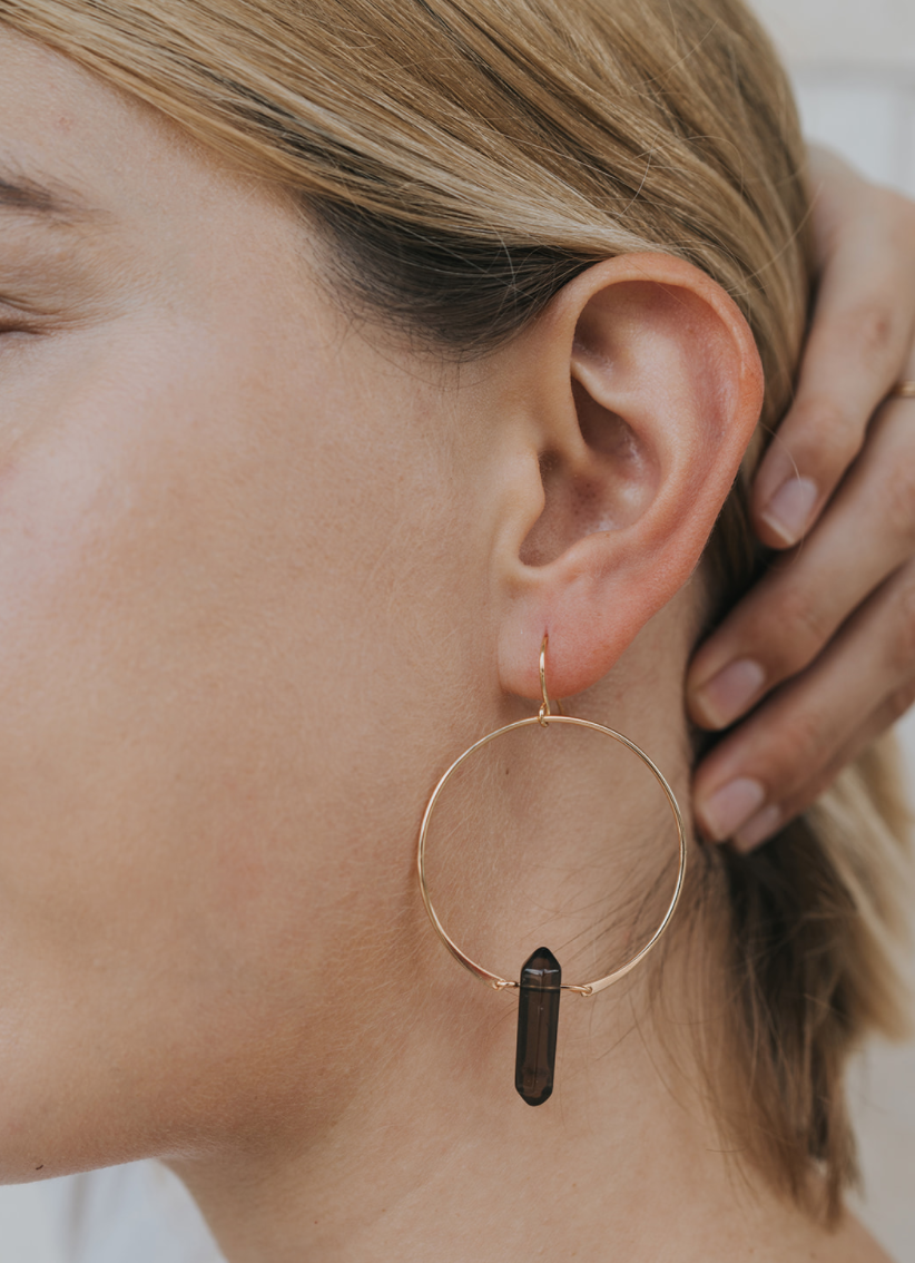 Close-up of an ear wearing a gold hoop earring with a black accent.