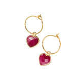 Gold hoop earrings with pink heart gemstones on a white background