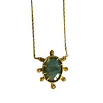 A close up of a pendant necklace with a large oval shaped blue gemstone surrounded by 8 smaller beige gemstones on a white backgrouns