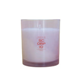 A clear glass jar candle with pale lavender wax and orange-red printed text reading 'SC ORP IO' centered on a white background.