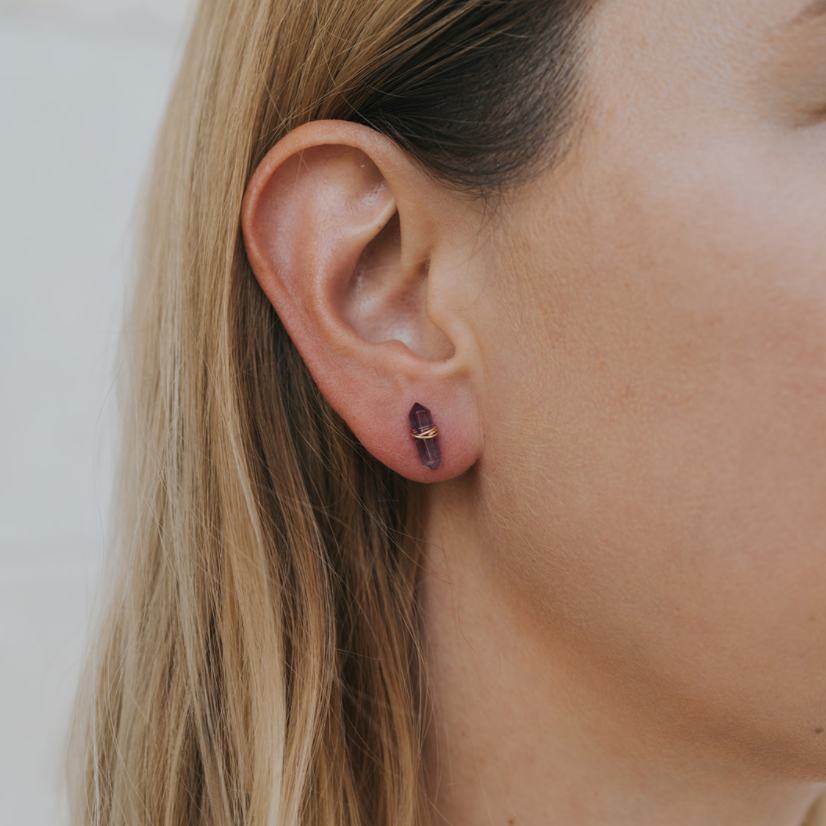 Close-up of a person wearing a small earring with a neutral background