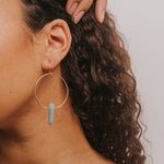 Woman with hoop earrings and a strapless top against a plain background