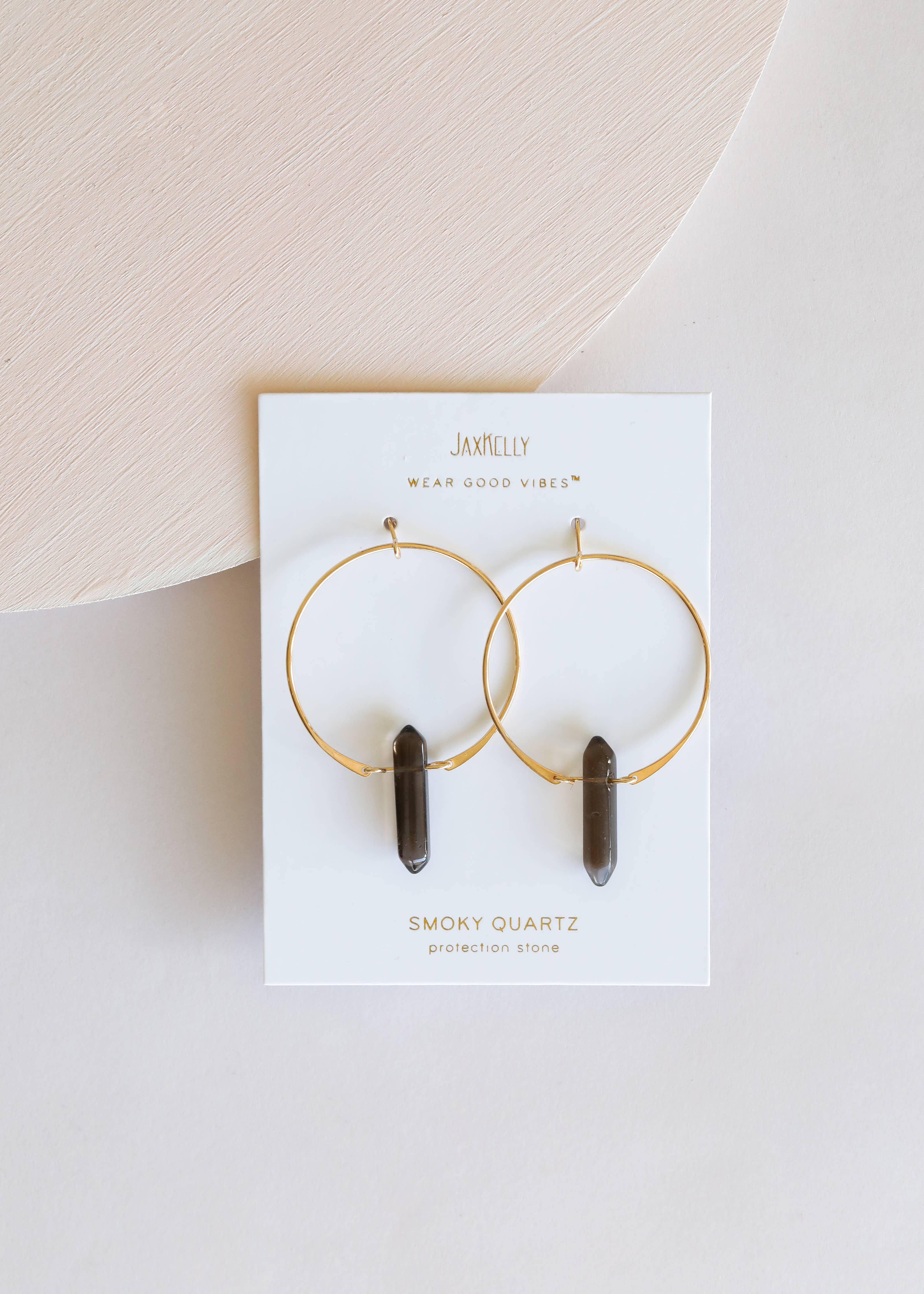 Jamelily earrings with smoky quartz stones on a white card against a beige background