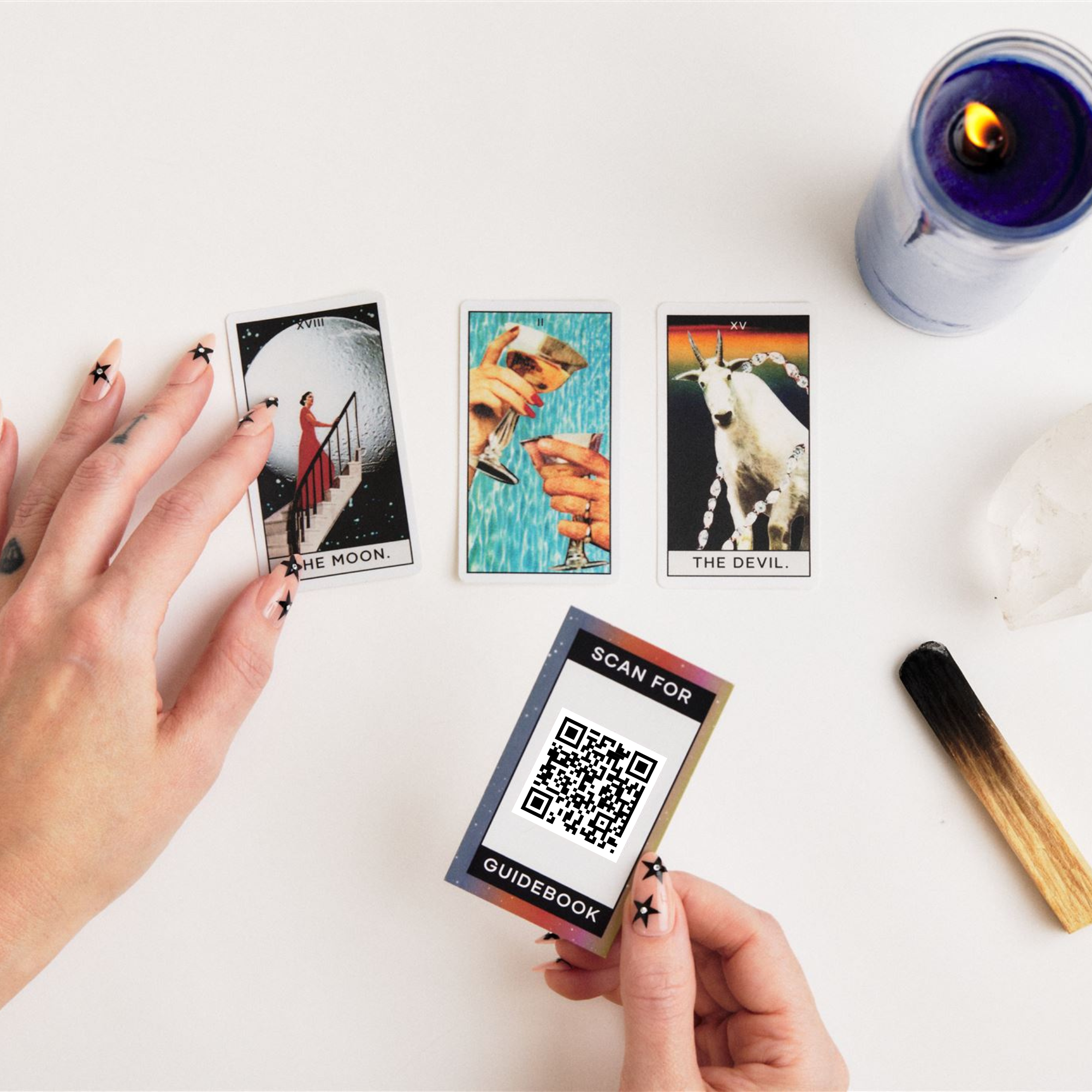 Hands holding tarot cards with a QR code card on a white surface.