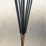 Set of black incense sticks on a beige stone surface