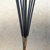 Set of black incense sticks on a beige stone surface