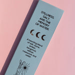 A light blue rectangular product box for Brass Earth incense sticks, photographed diagonally on a soft pink background. The box features black text describing a scent profile ('Stillness, Salt, and the Memory of Water') and a simple rabbit illustration.
