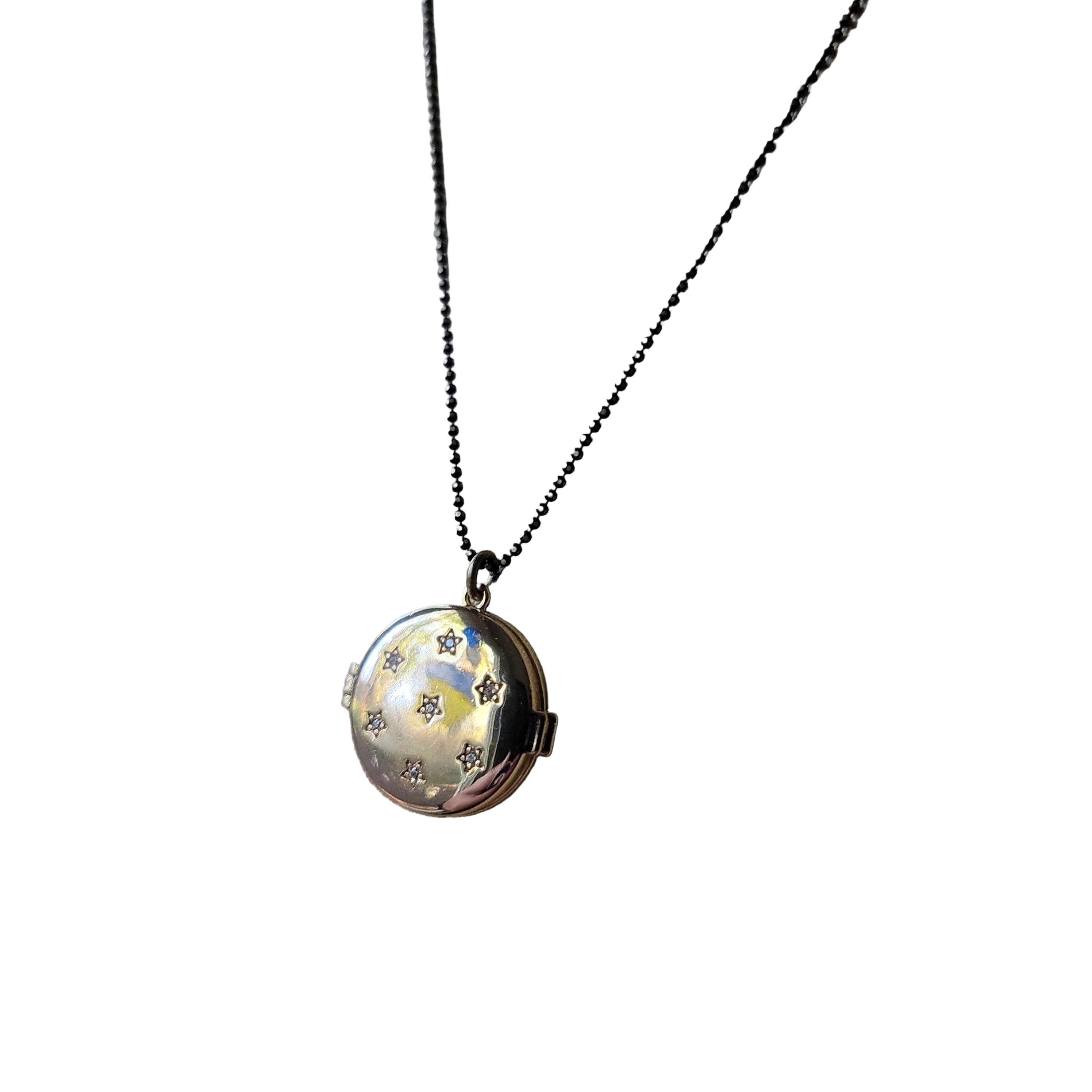 Gold locket necklace on a beige fabric background