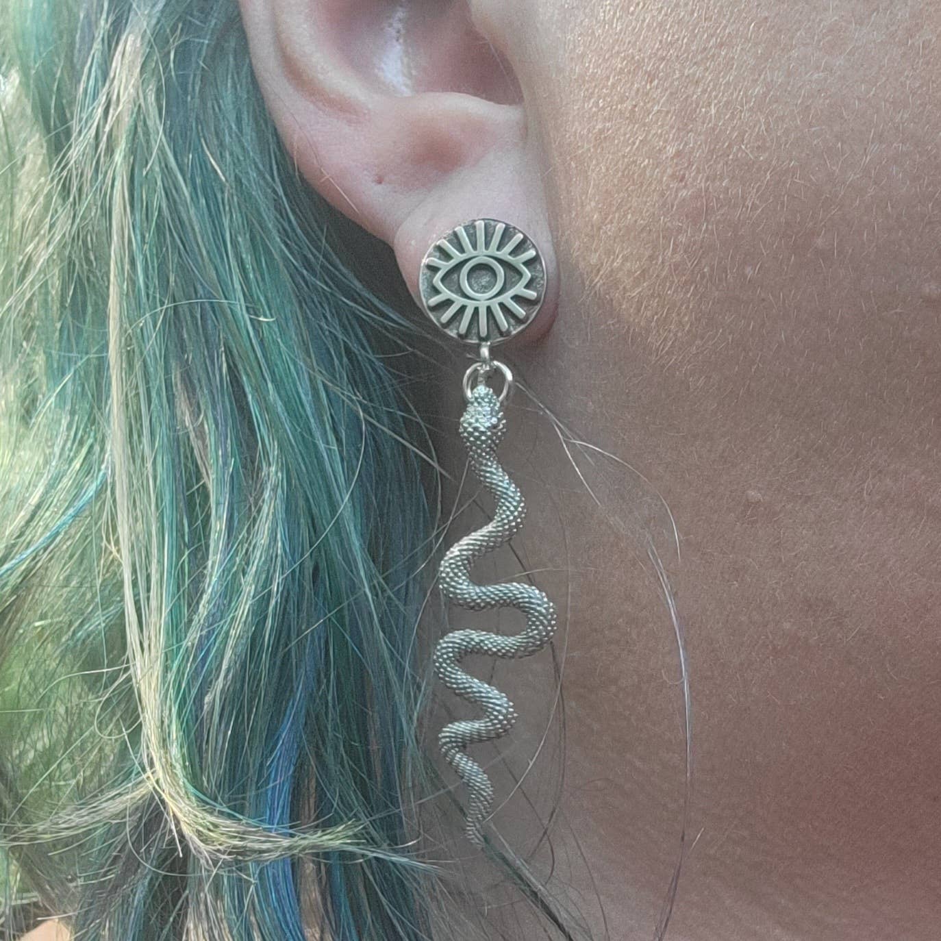 Earring with snake design worn by a person with green hair