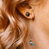 Close-up of an ear with a gold threader earring featuring a blue moon pendant.
