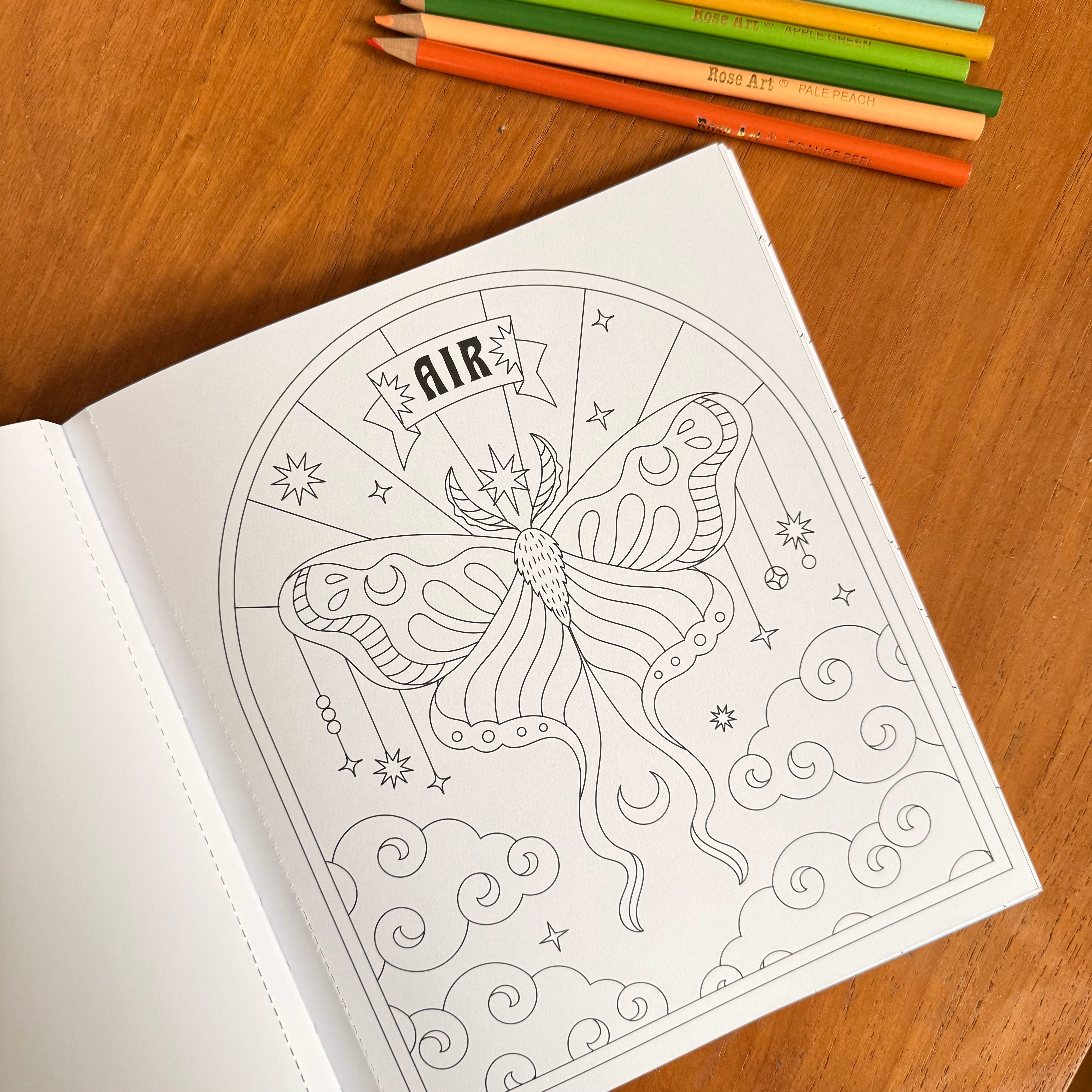 An open coloring book on a wooden table, showing a black-and-white line art page of a butterfly with the word 'AIR' at the top. Color pencils are lined up at the top of the frame.