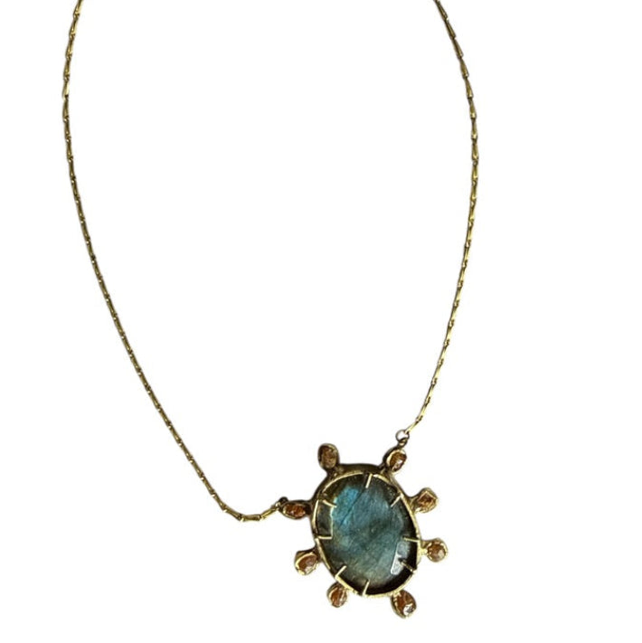 A pendant necklace with a large blue gem surrounded by smaller beige brown gems on a white background