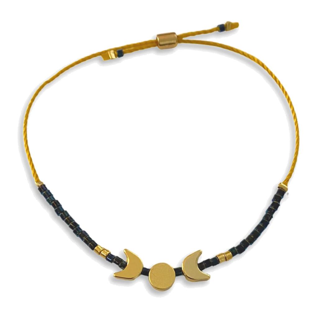 Bracelet with gold and black beads and moon phase charms on a white background