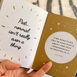 Book open to pages with motivational quotes, held by a hand.