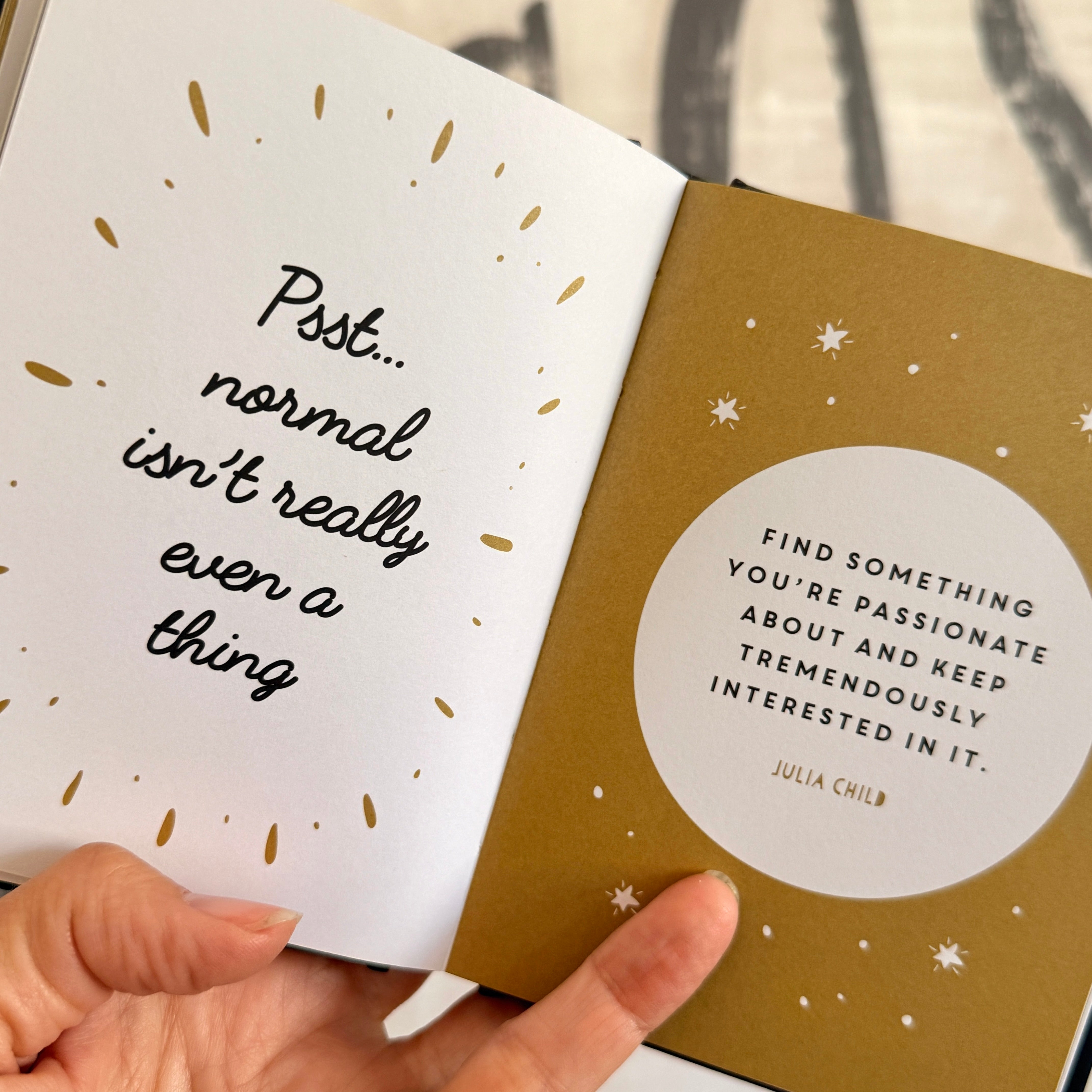 Book open to pages with motivational quotes, held by a hand.