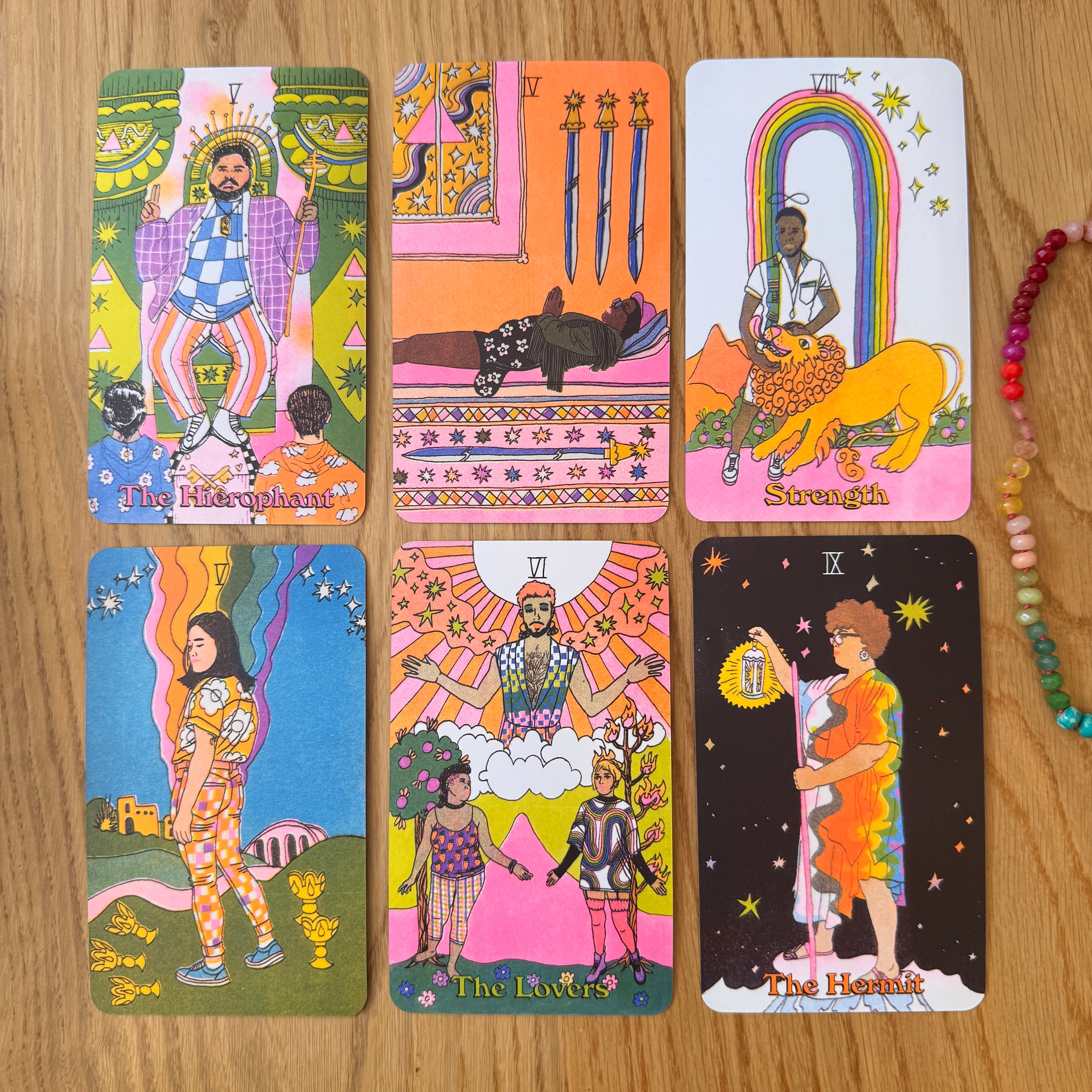 Set of colorful tarot cards on a wooden surface with a bracelet.
