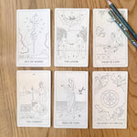 Set of tarot cards on a wooden surface with pencils.