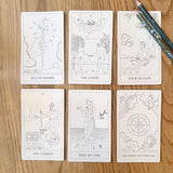 Set of tarot cards on a wooden surface with pencils.