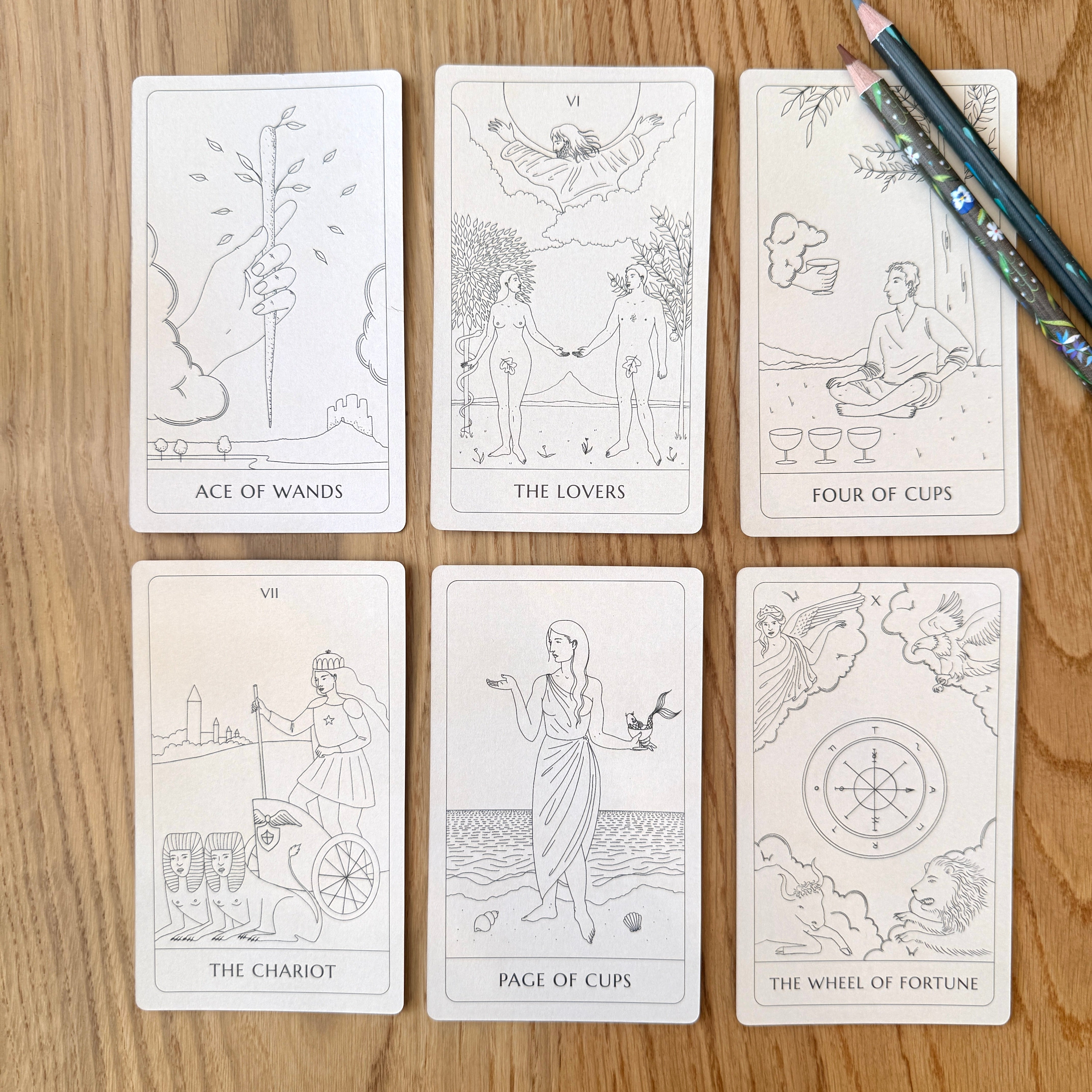Set of tarot cards on a wooden surface with pencils.