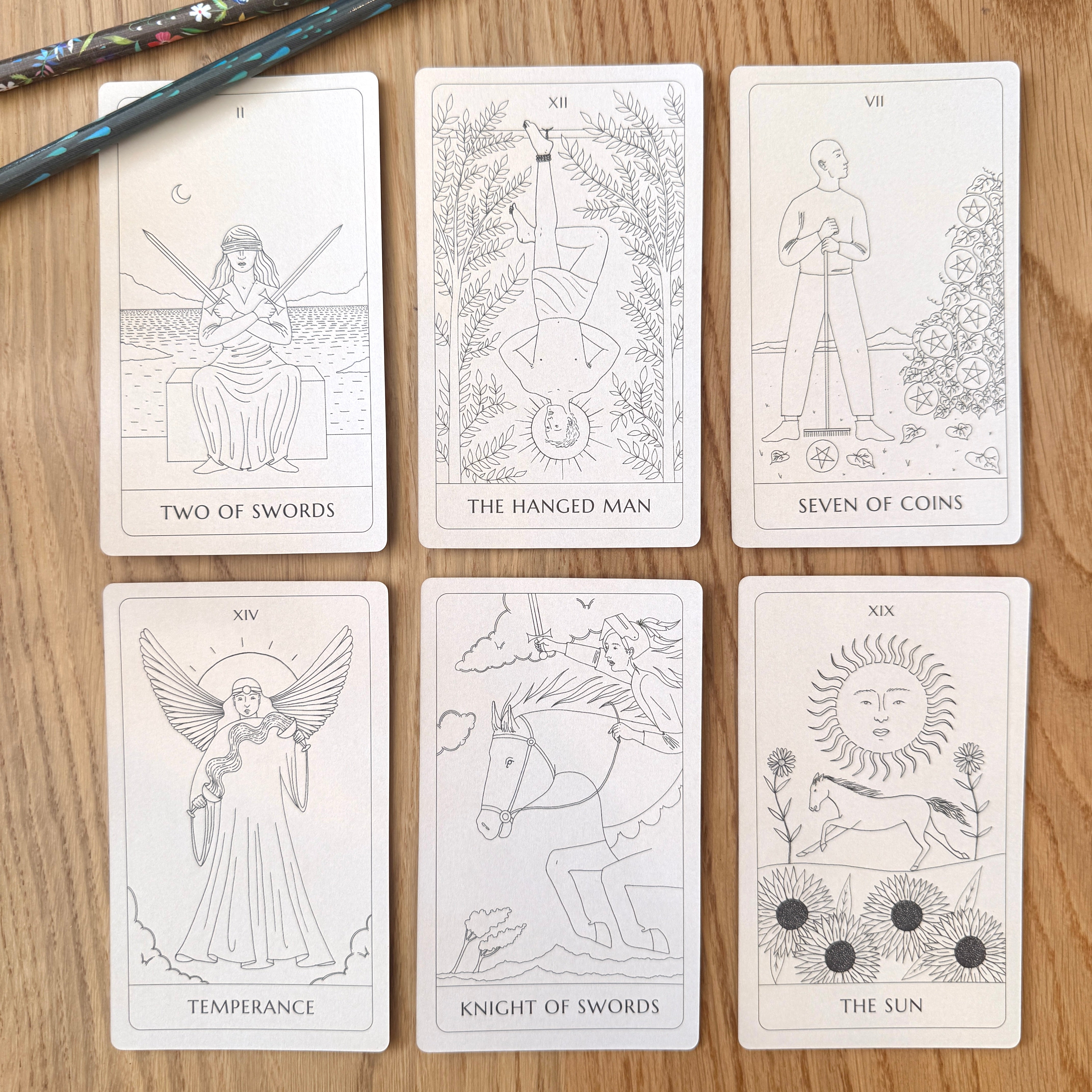 Set of tarot cards on a wooden surface with a pencil.