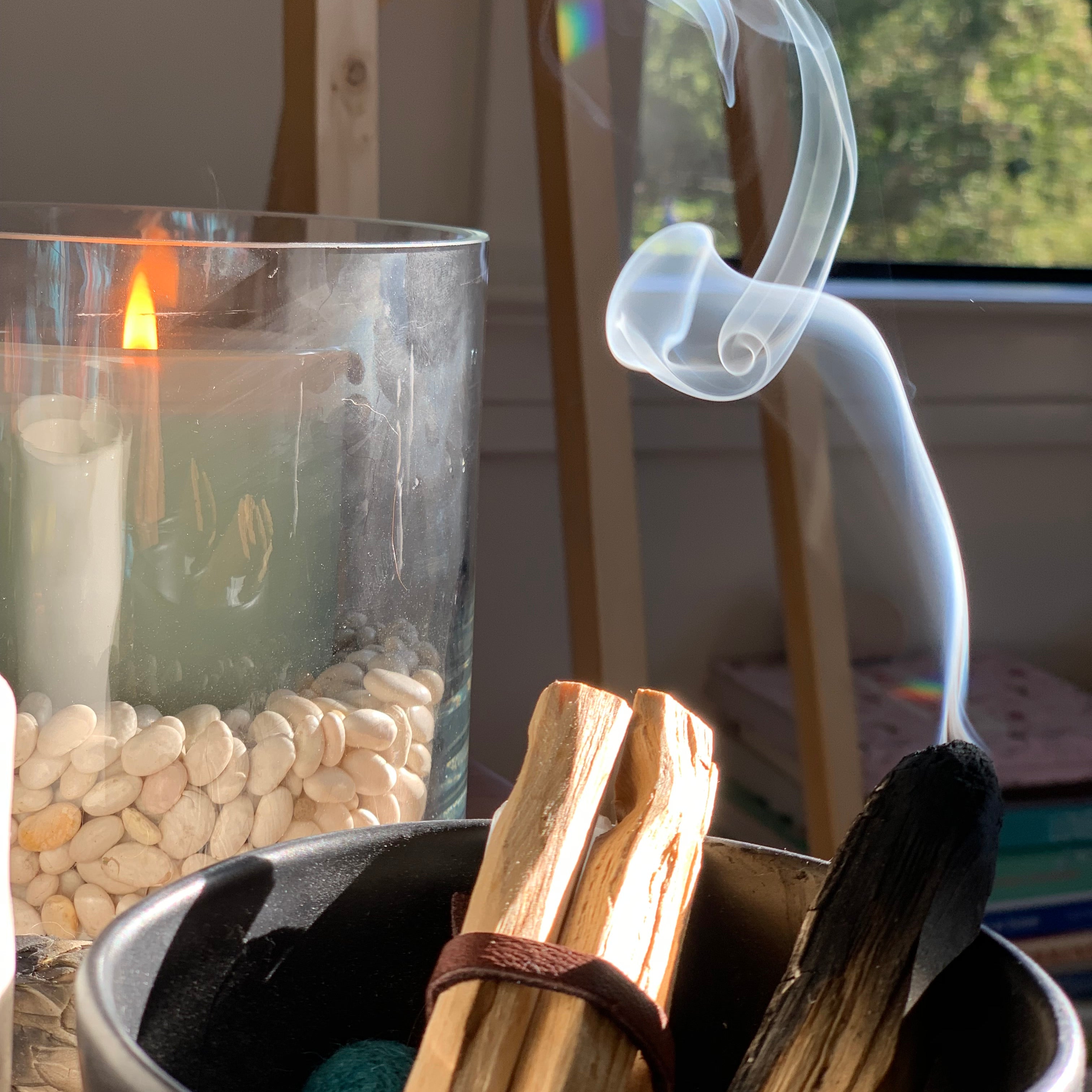 Black incense burner with sticks and transparent smoke in a blurred indoor setting