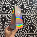 Hand holding a magical mystery iridescent bag against a black and white geometric patterned background