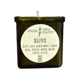 Green candle in a glass container with a label on a white background