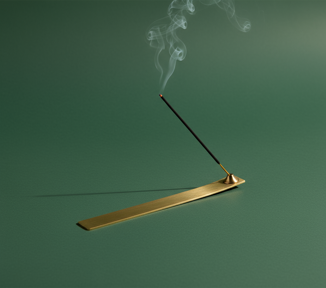 Gold incense burner with a smoking incense stick on a green background