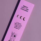 A tall, narrow lavender-pink product box for Brass Earth, featuring black text and illustrations including a rabbit and moon phases, photographed on a matching lavender background.