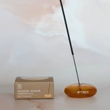 Wooden incense holder with a single stick of incense on a light background