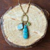 Necklace with turquoise and green stone pendants on a wooden surface