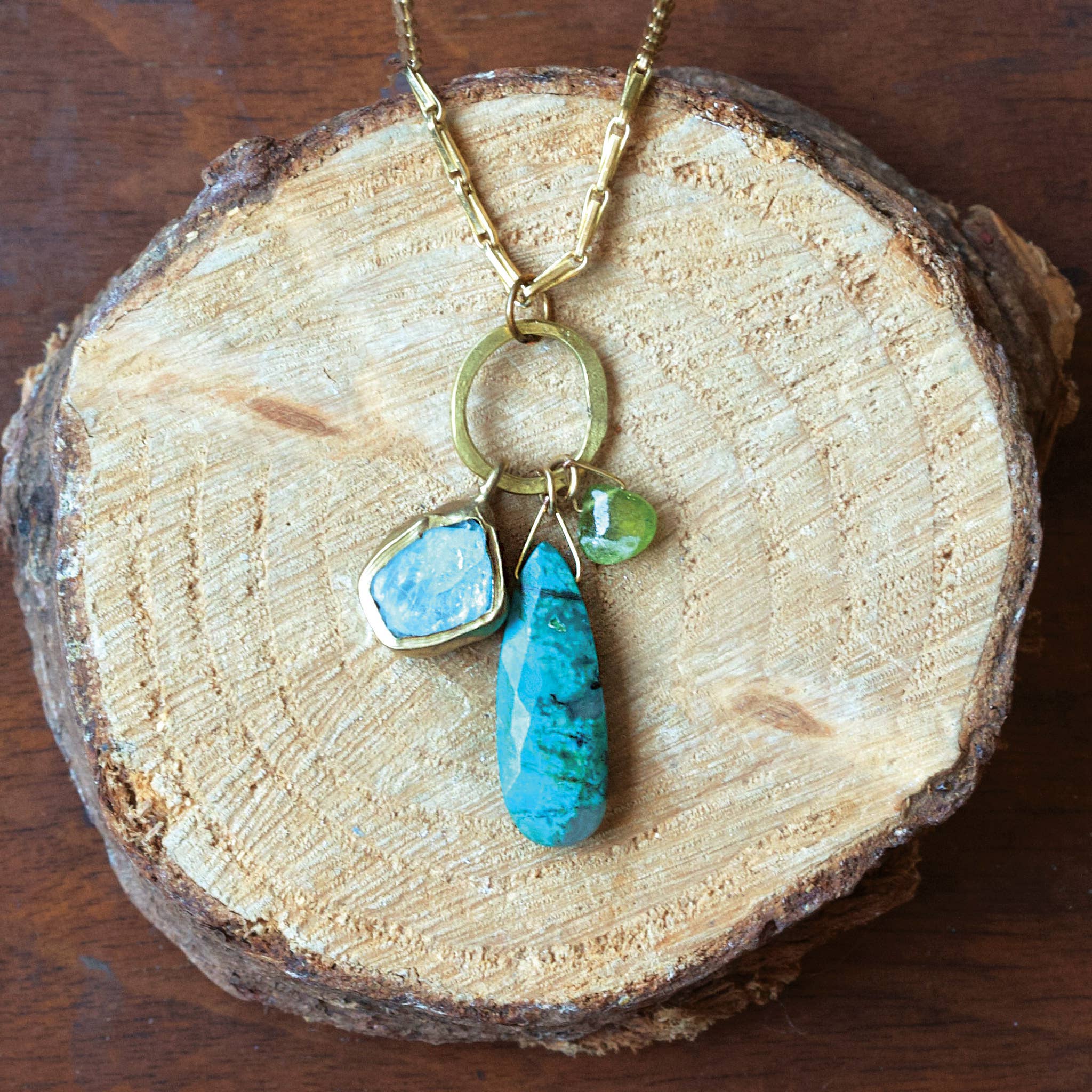 Necklace with turquoise and green stone pendants on a wooden surface