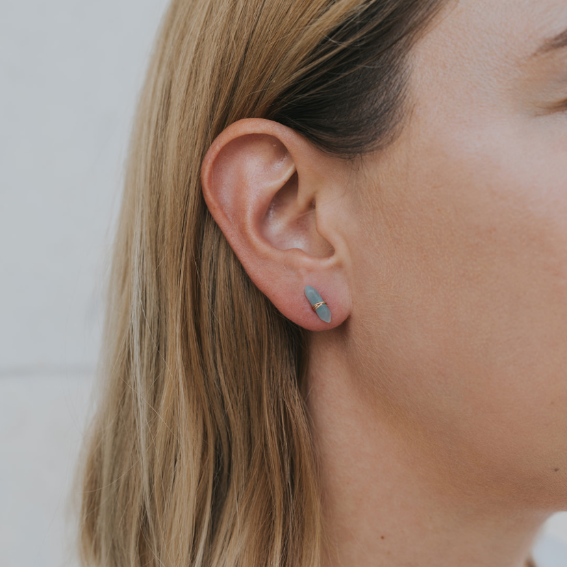 Close-up of a person wearing a small earring with a neutral background