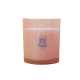 A pink glass jar candle with a single wick, featuring the text 'SAGITTARIUS' in blue on the front, set against a white background.