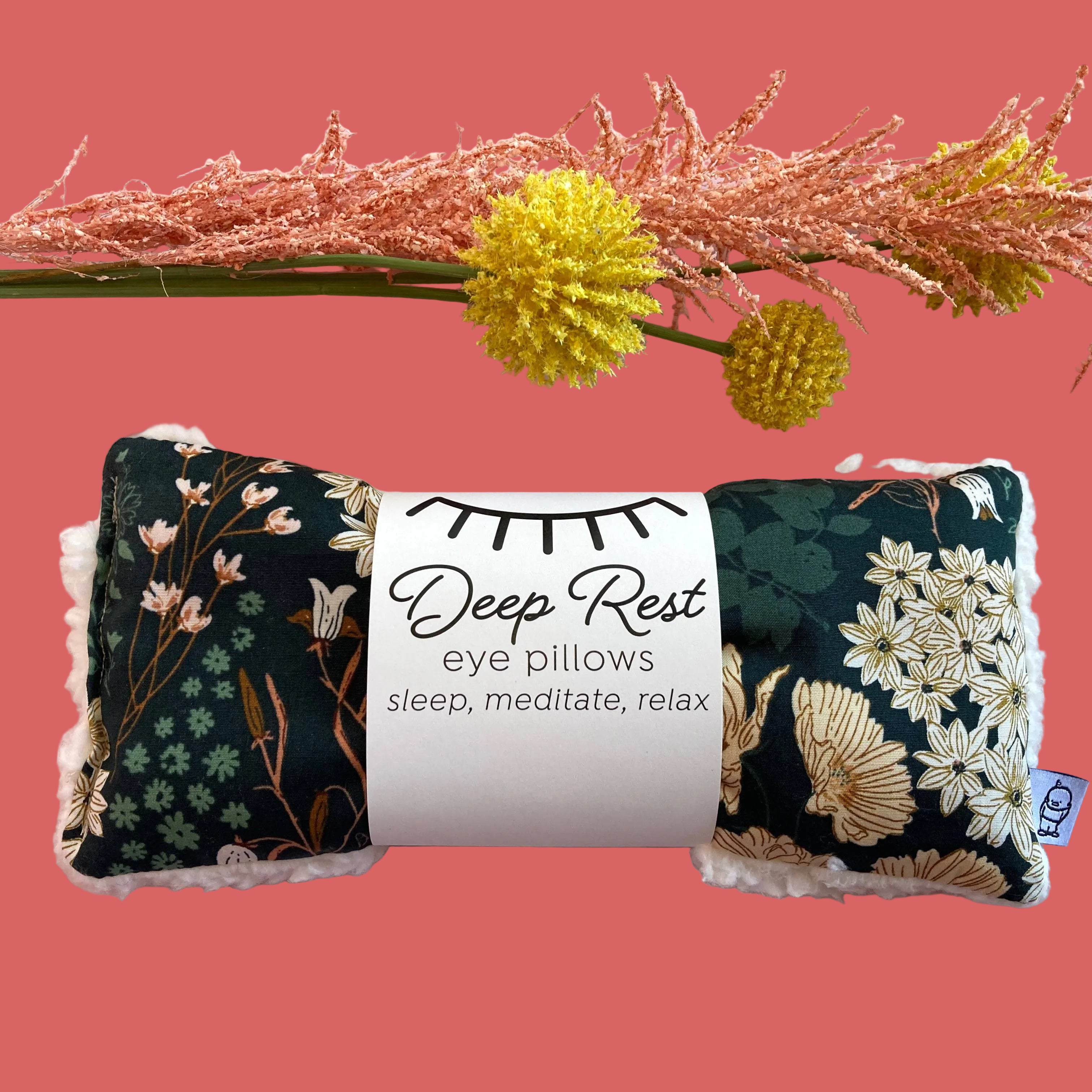 Floral eye pillows with a label on a pink background