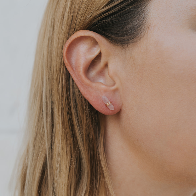 Close-up of a person's ear with a small earring on a neutral background