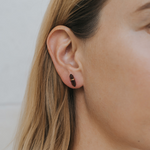 Close-up of a person wearing a gold hoop earring with a blurred background