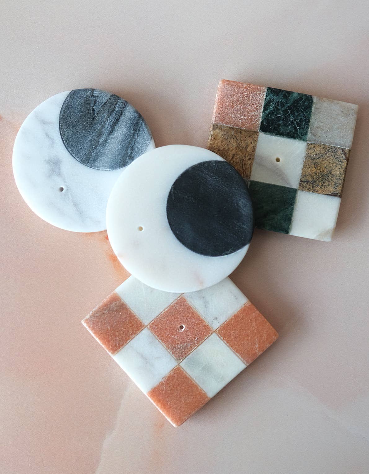 Set of marble incense holders with different patterns on a light pink background