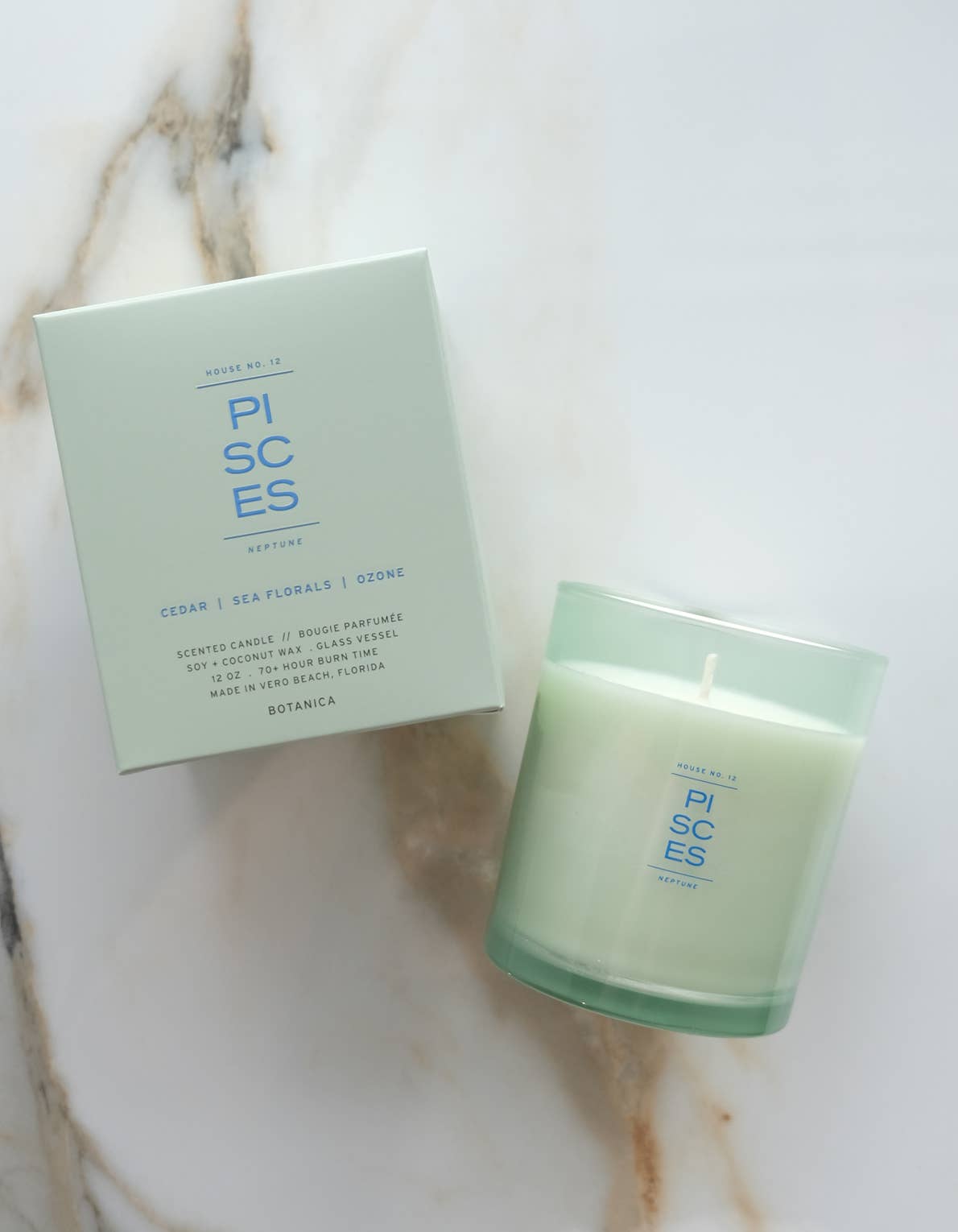 Green candle and packaging on a marble surface