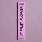 A tall, narrow pink box for Grass Earth Fruit Flower incense sticks, shown vertically against a matching dusty lavender background.