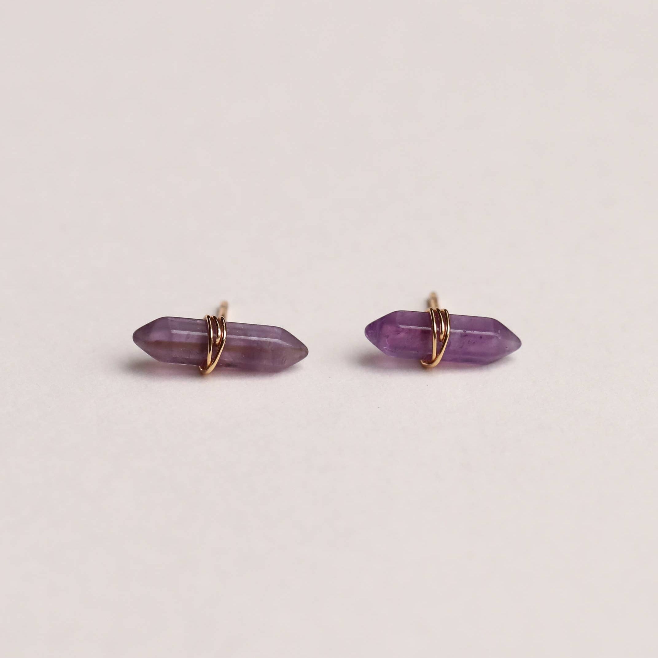 Amethyst crystal earrings on a light beige background